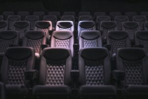 Rij lege theaterstoelen in zacht licht, symbool voor het loslaten van de rol en het thuiskomen in bewustzijn.