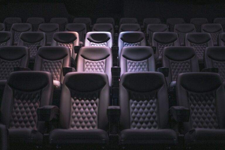 Rij lege theaterstoelen in zacht licht, symbool voor het loslaten van de rol en het thuiskomen in bewustzijn.