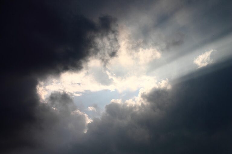 Donkere wolken waar licht doorheen breekt, als symbool voor het herkennen van angst en de ruimte die daarna ontstaat.