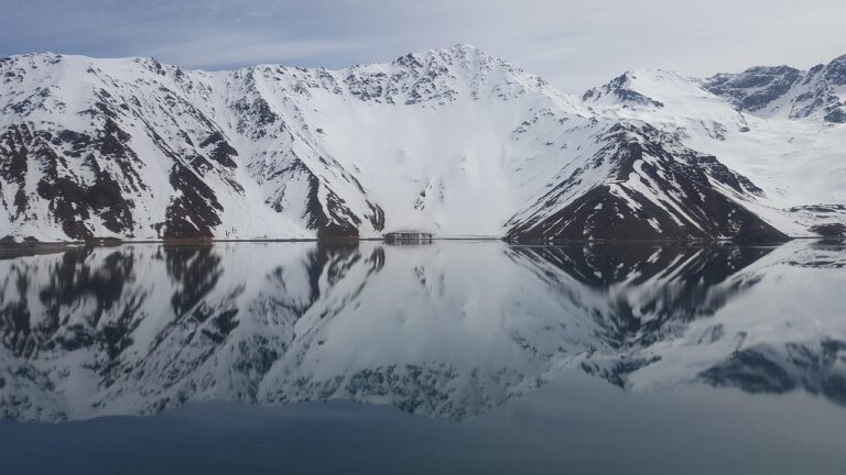 Bergen met sneeuw weerspiegeld in stil water als symbool voor innerlijke verstilling en herinnering