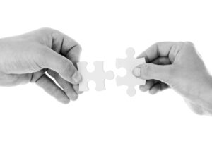 Twee handen met passende puzzelstukjes als symbool voor verbinding bij menselijke conflicten