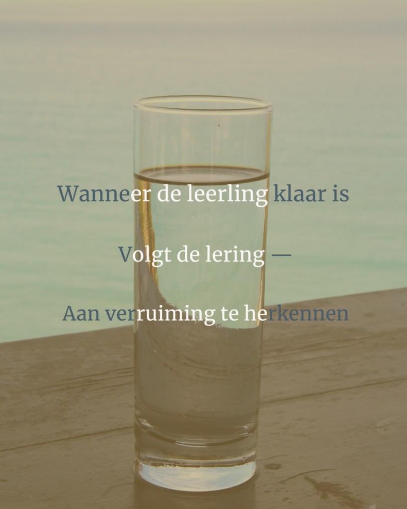 Horizon van zee en lichtblauwe lucht met op de voorgrond een tafel en een glas stilstaand water dat de zee weerspiegelt.