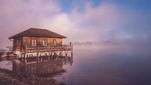 Tijd als illusie zichtbaar in een mistig meer met botenhuis bij zonsopgang